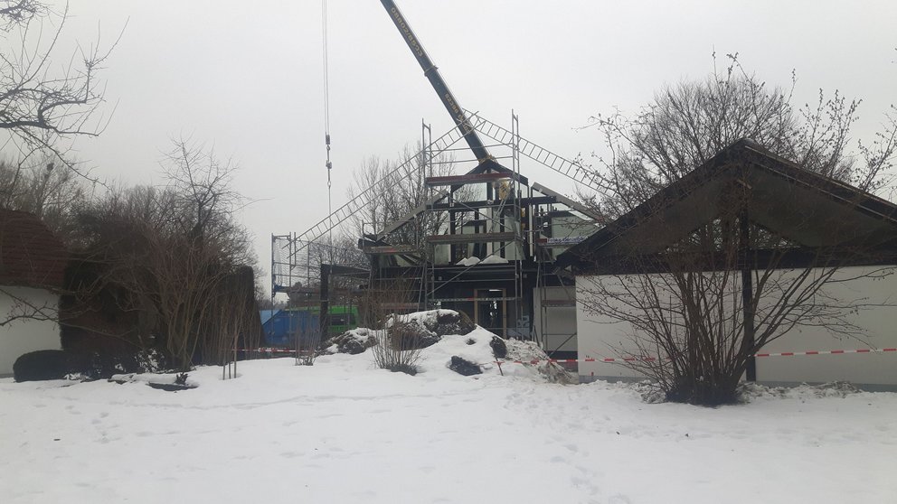 Bauarbeiten in verschneiter Umgebung Kran hebt Materialien für ein Bauprojekt in einer winterlichen Landschaft