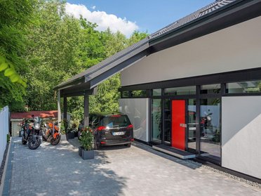 Elegantes Haus mit roter Tür, Garage und Pflanzen im Eingangsbereich