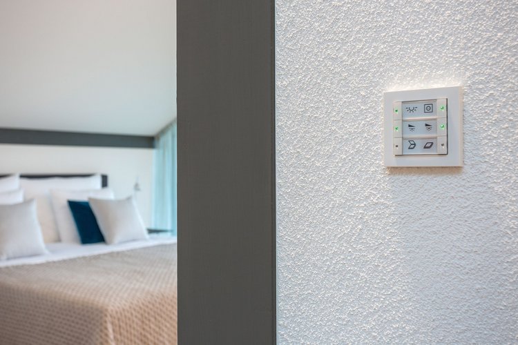 Lichtschalter im Fokus mit Blick auf ein stilvolles Hotelzimmer