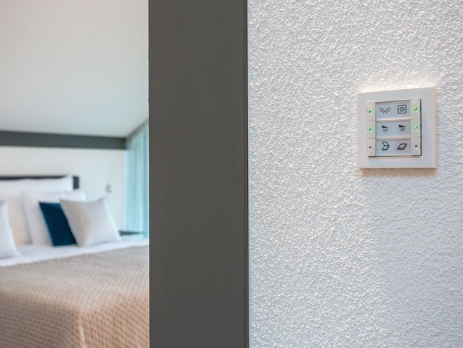 Moderne Lichtsteuerung in Hotelzimmeransicht Lichtschalter im Fokus mit Blick auf ein stilvolles Hotelzimmer