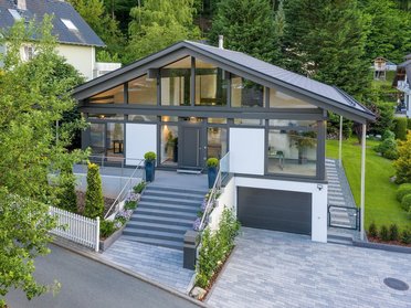 Blick auf ein Architektenhaus mit eleganter Außenanlage und Bäumen