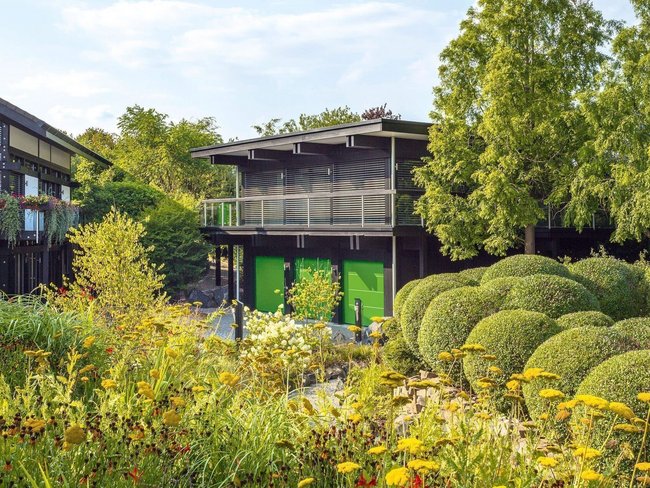 Ansicht eines HUF Hauses mit gepflegtem Garten und Bürogebäude