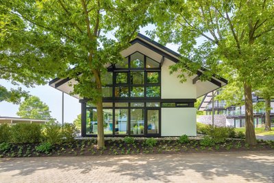 Modum7 10 Aussenansicht 1 Ein modernes Gebäude mit großen Fenstern, umgeben von Bäumen und Grünflächen.