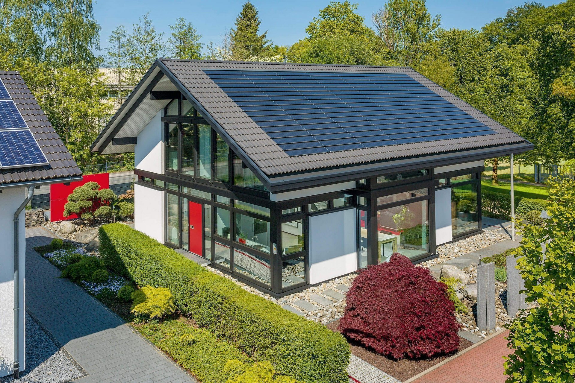 Ansicht einer modernen Villa mit Solarpanelen und gepflegtem Garten