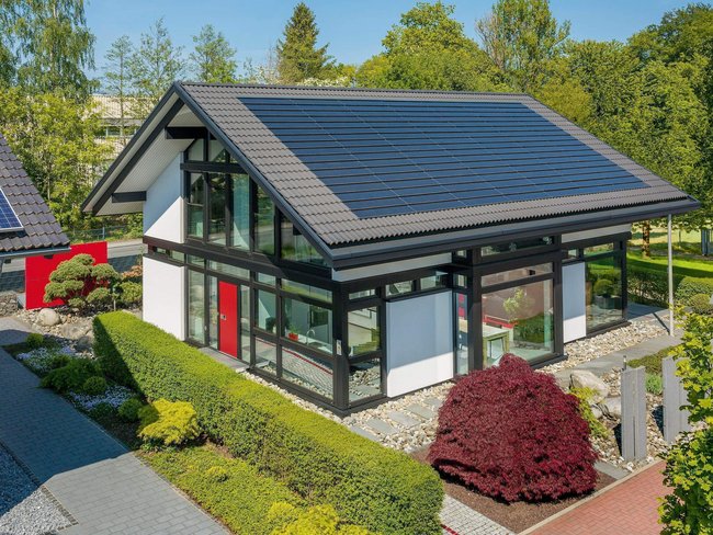 Moderne Villa mit Solaranlage und Garten Ansicht einer modernen Villa mit Solarpanelen und gepflegtem Garten