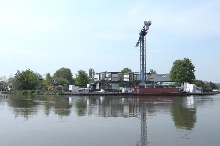 Eine Baustelle am Wasser mit Kränen und Baumaterialien