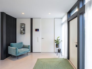 Lichtdurchflutetes Architektenhaus im modernen Stil Heller Eingangsbereich mit Sofa und grüner Matte