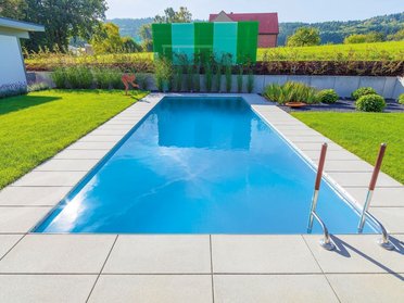 Ein HUF Haus mit einem blauen Pool und gepflegtem Garten.