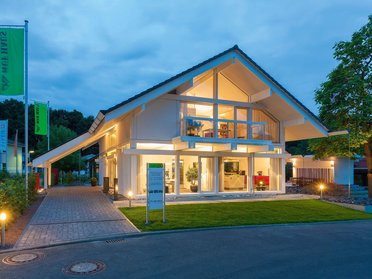 Ein modernes Wohnhaus mit Beleuchtung und Rasenfläche.