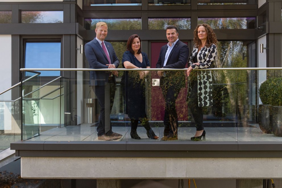 Professionals on a modern balcony Four individuals standing on a balcony of a modern building