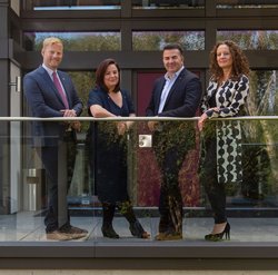 Professionals on a modern balcony Four individuals standing on a balcony of a modern building