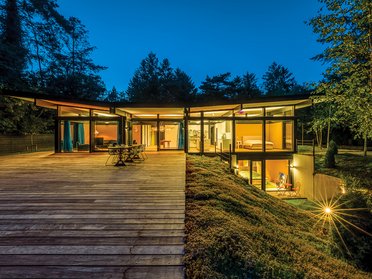 Moderne HUF Bungalow bei Nacht mit Beleuchtung Traumhaftes modernes Haus mit großen Fenstern und Terrasse