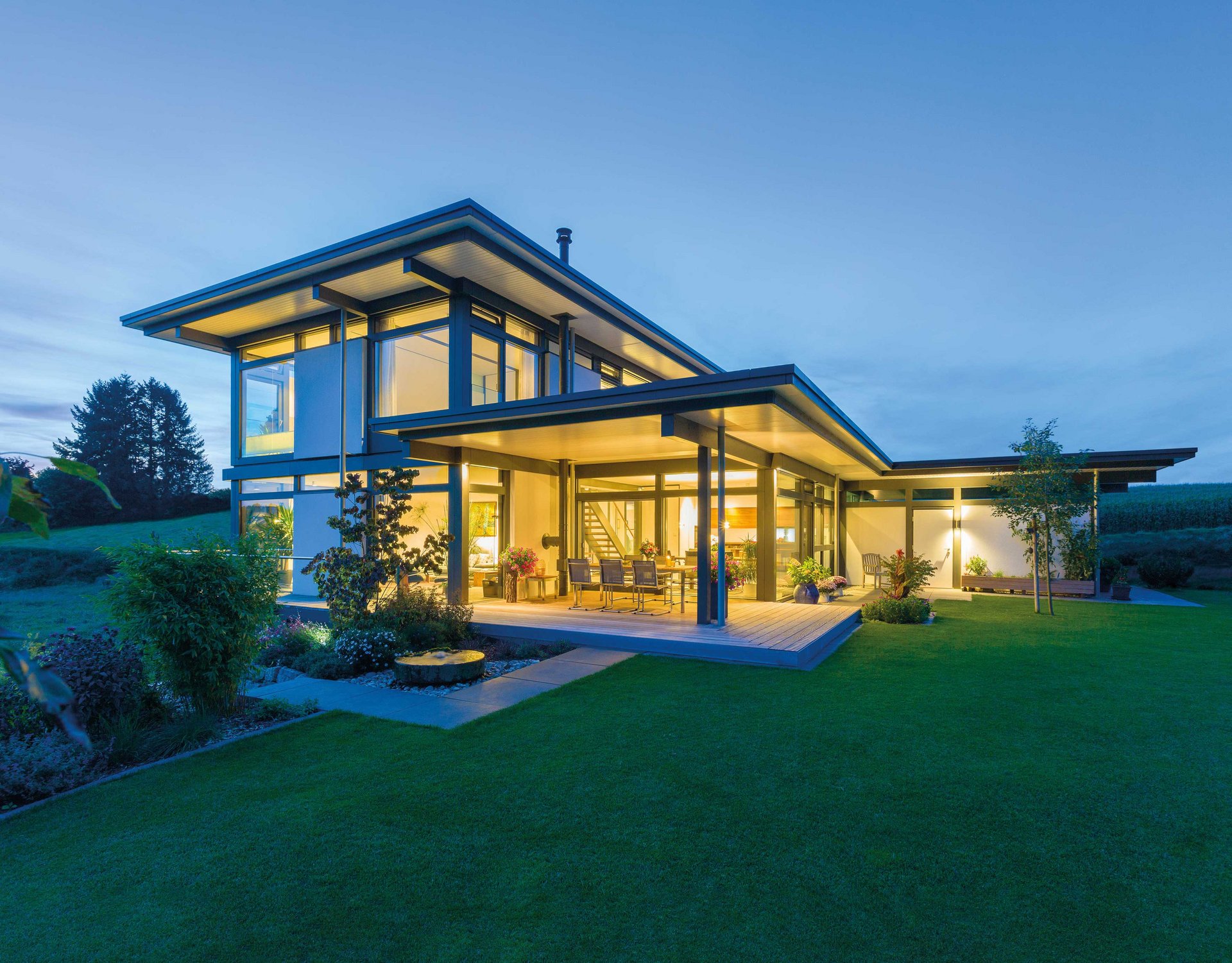 Modernes HUF HAUS im Abendlicht mit großzügigem Garten