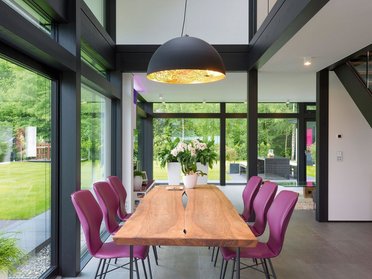 Modernes Esszimmer mit großer Holzplatte und eleganten Stühlen