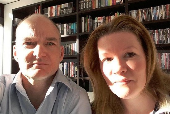 Two people posing for a photo with bookshelves in the background