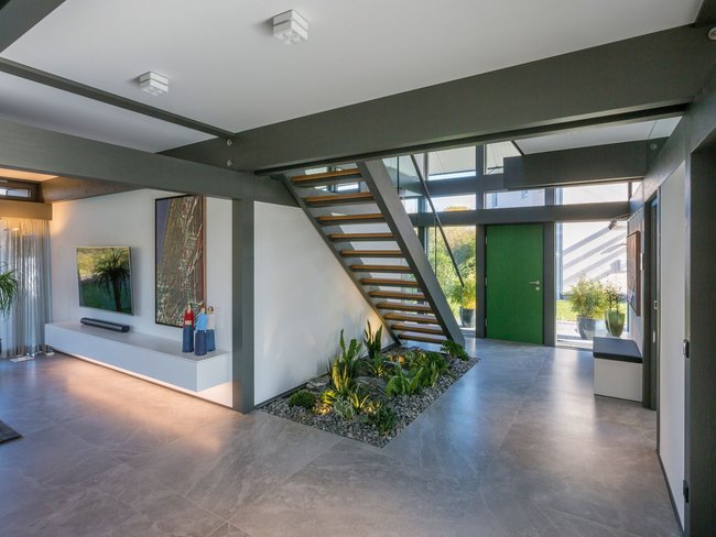 Modernes Wohnambiente mit Eingang und Treppe Helle Eingangshalle mit Treppe, Pflanzen und modernem Dekor