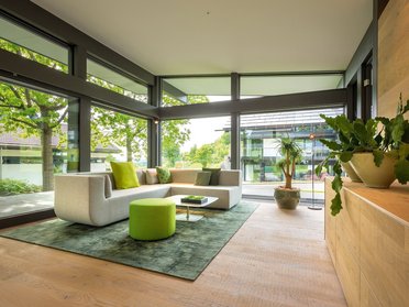 Modernes Wohnzimmer mit großen Fenstern und Grünflächen Helles Wohnzimmer mit modernem Möbeldesign und Pflanzen