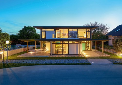 Ansicht eines modernen Hauses mit großen Fenstern und Außenbeleuchtung