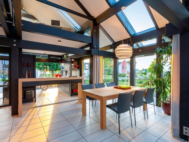 HUF Musterhaus Koblenz ebenholz 1 Helles Esszimmer mit Tisch, Stühlen und Pflanzen.