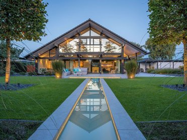 Modernes Fachwerkhaus mit Garten und Bachlauf Transparente Architektur aus Holz und Glas in idyllischer Umgebung