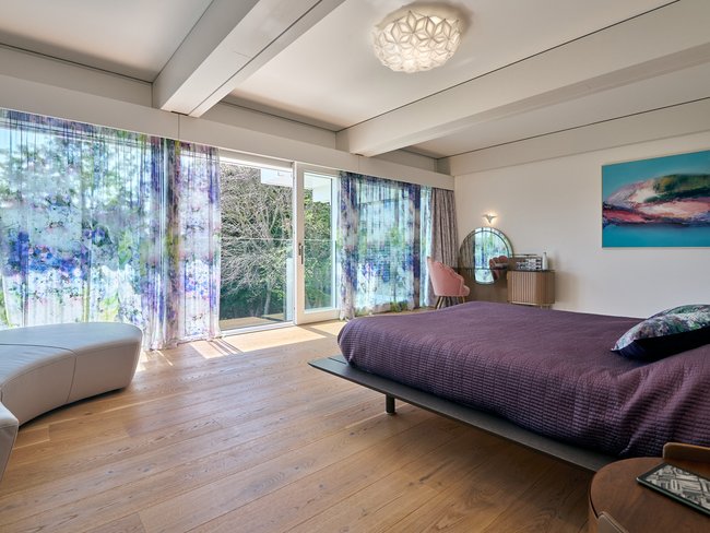 Elegantes Schlafzimmer mit Blick auf die Natur und großzügigen Fenstern