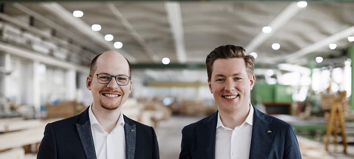 Zwei Männer stehen in einer Holzwerkstatt Freundliche Männer in Anzügen vor Holzregalen in einer Werkstatt