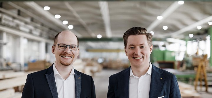 Zwei Männer stehen in einer Holzwerkstatt Freundliche Männer in Anzügen vor Holzregalen in einer Werkstatt