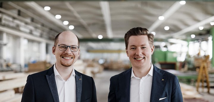 Zwei Männer stehen in einer Holzwerkstatt Freundliche Männer in Anzügen vor Holzregalen in einer Werkstatt