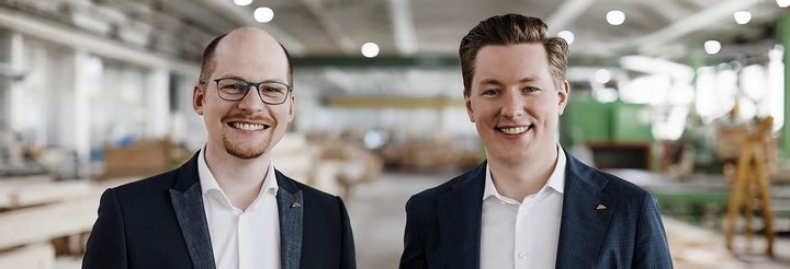 Freundliche Männer in Anzügen vor Holzregalen in einer Werkstatt