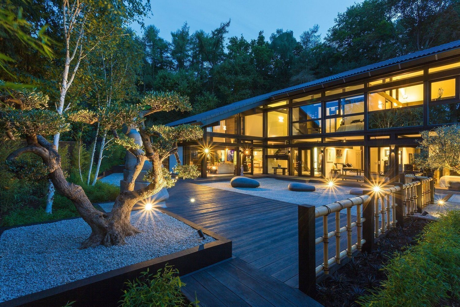 Ein HUF Haus mit Glasfassade, Garten und eleganten Außenpool bei Nacht.