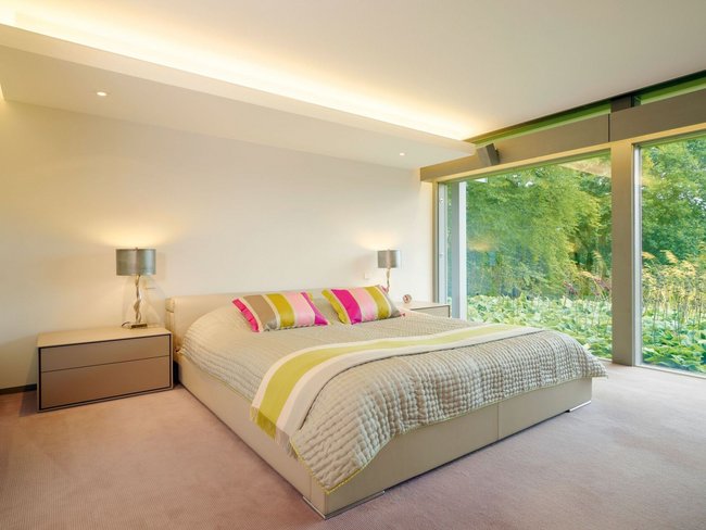 Modernes Schlafzimmer im HUF Bungalow mit Glasfront Schlafzimmer mit komfortablem Bett und großen Fenstern im HUF Bungalow