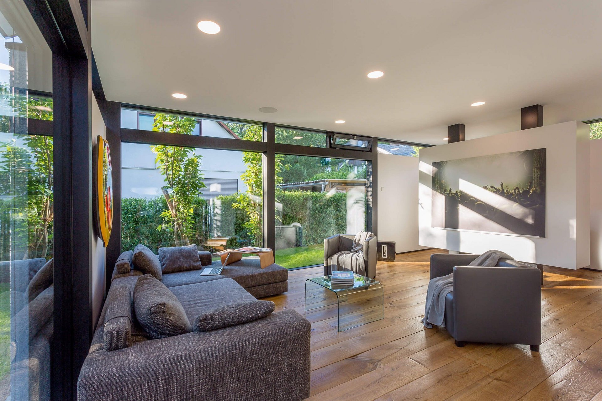 Modernes Wohnzimmer mit großflächigen Fenstern Helles Wohnzimmer mit Holzfußboden und stilvollen Möbeln