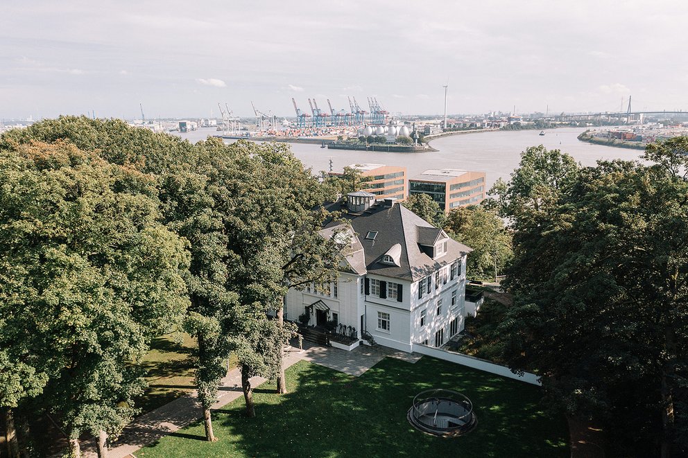 Elegantes Haus umgeben von Bäumen mit Hafenansicht im Hintergrund