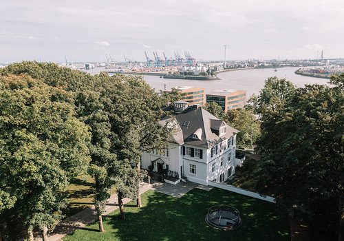 Elegantes Haus umgeben von Bäumen mit Hafenansicht im Hintergrund