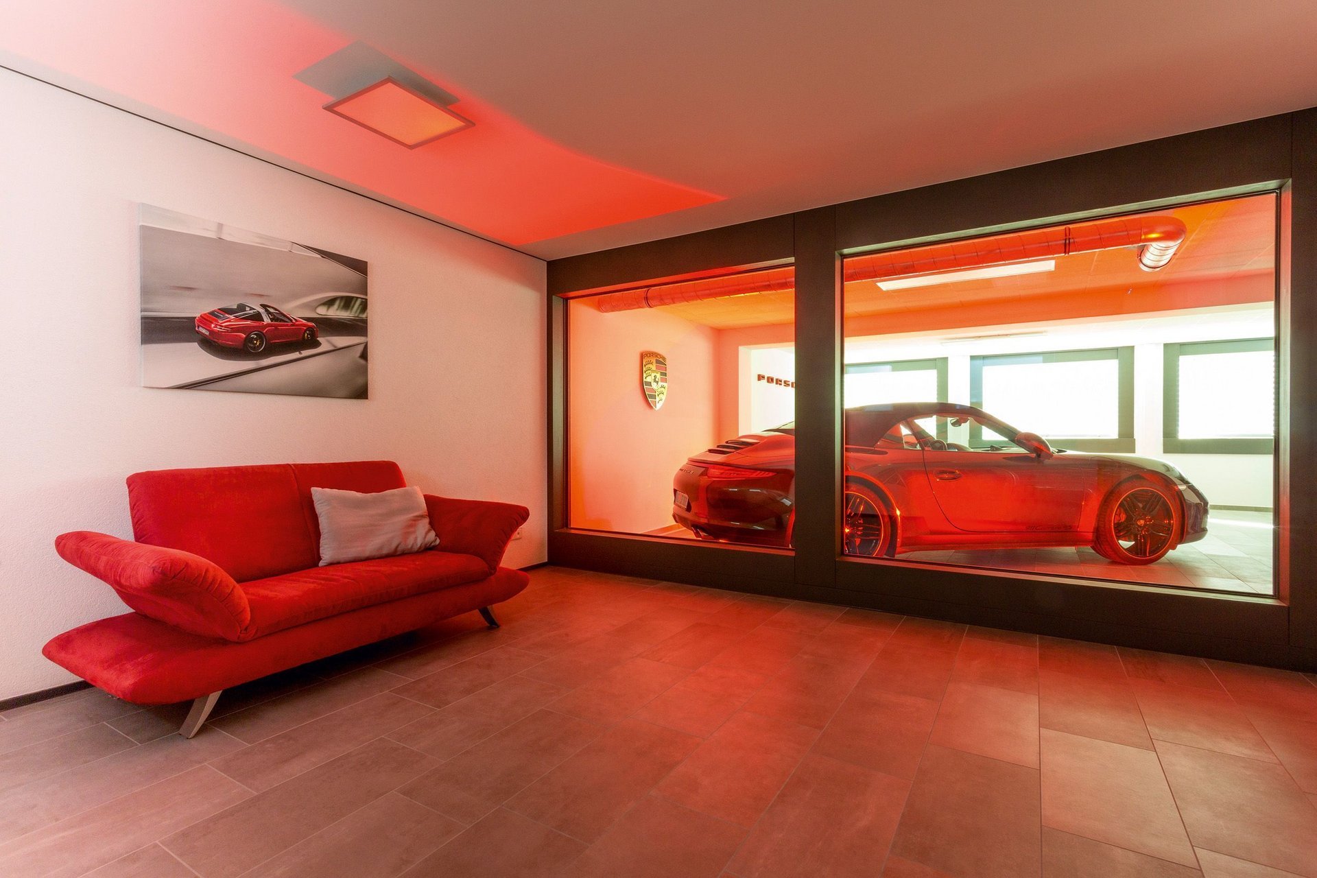 Bungalow mit rotem Sofa und Porsche in der Glasbox