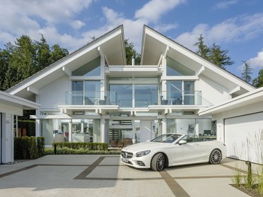 Architektonische Facade einer modernen Villa mit Garten und Auto