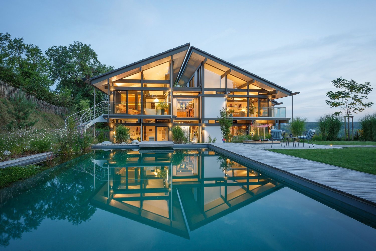 Modernes Architektenhaus mit Pool bei Sonnenuntergang Luxuriöses Premiumhaus mit Garten und Wasserreflexion
