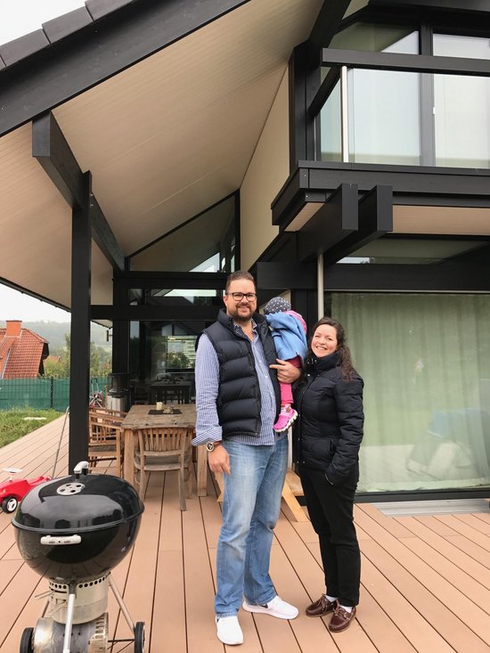 Familie posiert vor einem modernen Haus mit großen Fenstern
