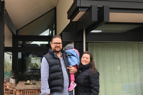 Familie posiert vor einem modernen Haus mit großen Fenstern