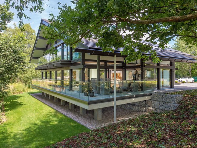 Futuristisches Gebäude mit flacher Dachkonstruktion und begrüntem Garten