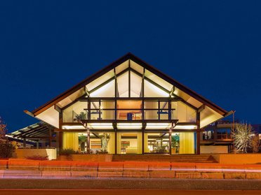 Elegantes Gebäude mit Glasfront und strukturierten Dächern bei Nacht