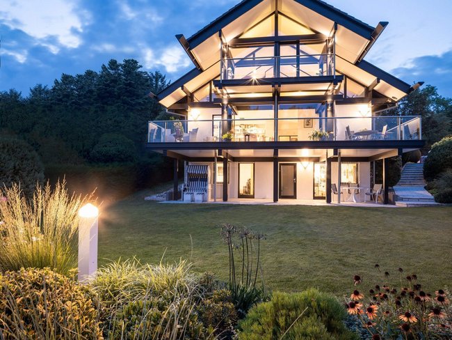 Moderne Architektur eines HUF Hauses mit Gartenbeleuchtung bei Dämmerung