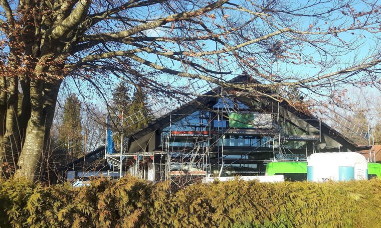 Renovierung eines modernen Gebäudes mit Gerüst Blick auf ein in Renovierung befindliches Gebäude mit Gerüst und Bäumen im Vordergrund