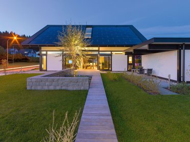 Futuristisches Gebäude mit grüner Umgebung und Holzweg