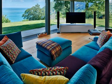 HUF Haus am Meer: Modernes Designhaus mit Meerblick Stylisches modernes Wohnzimmer mit Blick auf das Meer und farbenfrohen Kissen