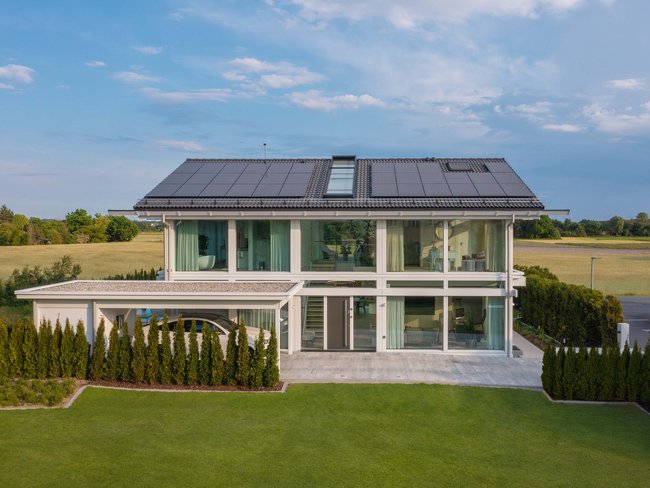 Ein modernes HUF Haus mit großen Fenstern und einer gepflegten Rasenfläche.