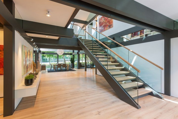 Lichtdurchfluteter Raum mit Holztreppe und modernen Kunstwerken