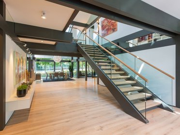 Lichtdurchfluteter Raum mit Holztreppe und modernen Kunstwerken