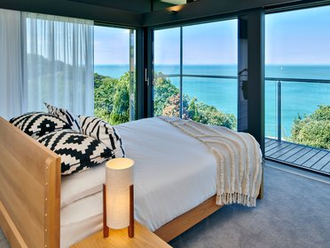 HUF Haus am Meer – Modernes Designhaus mit Aussicht Schlafzimmer im HUF Haus mit Blick auf das Meer und moderne Einrichtung