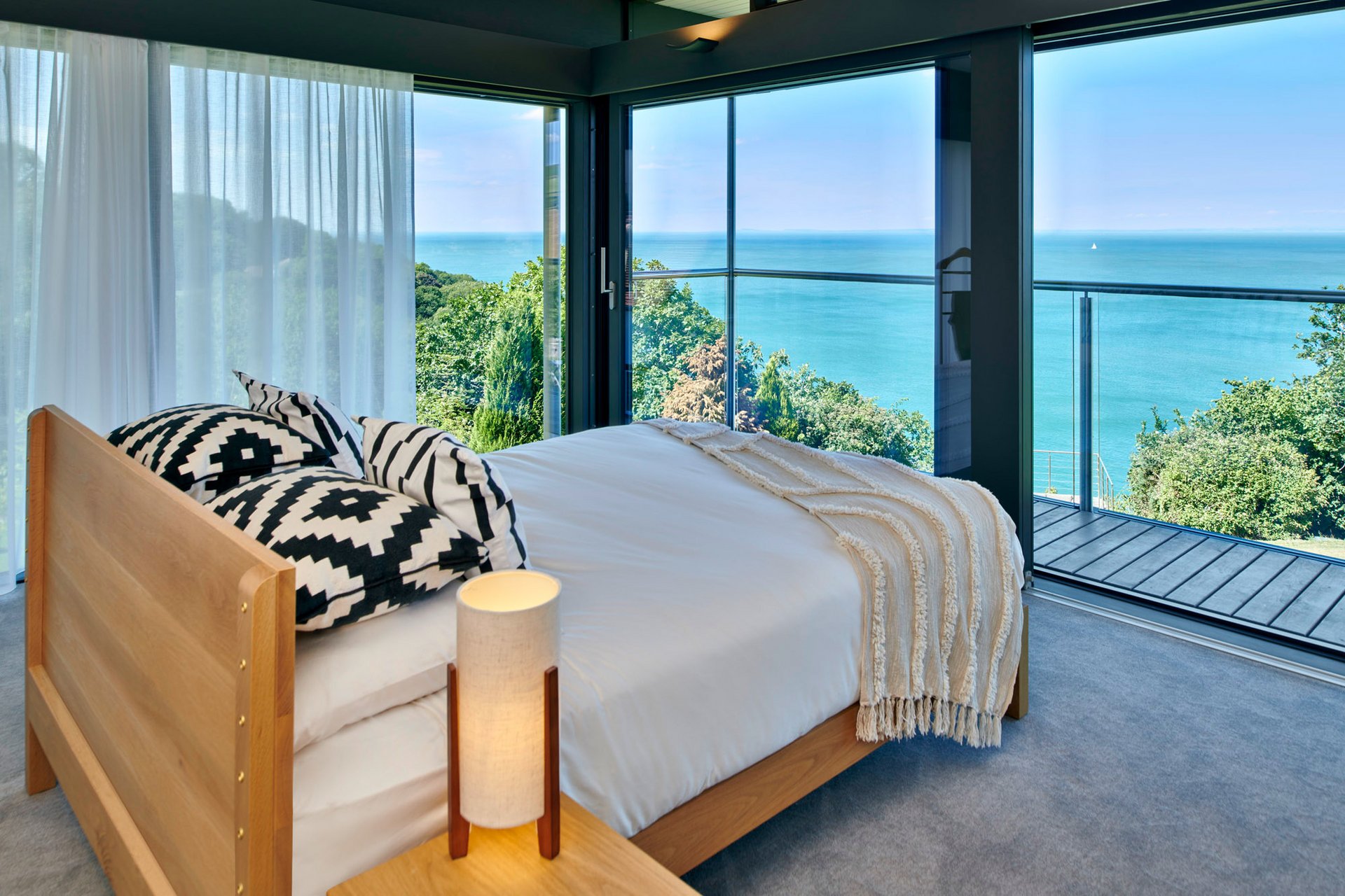 HUF Haus am Meer – Modernes Designhaus mit Aussicht Schlafzimmer im HUF Haus mit Blick auf das Meer und moderne Einrichtung
